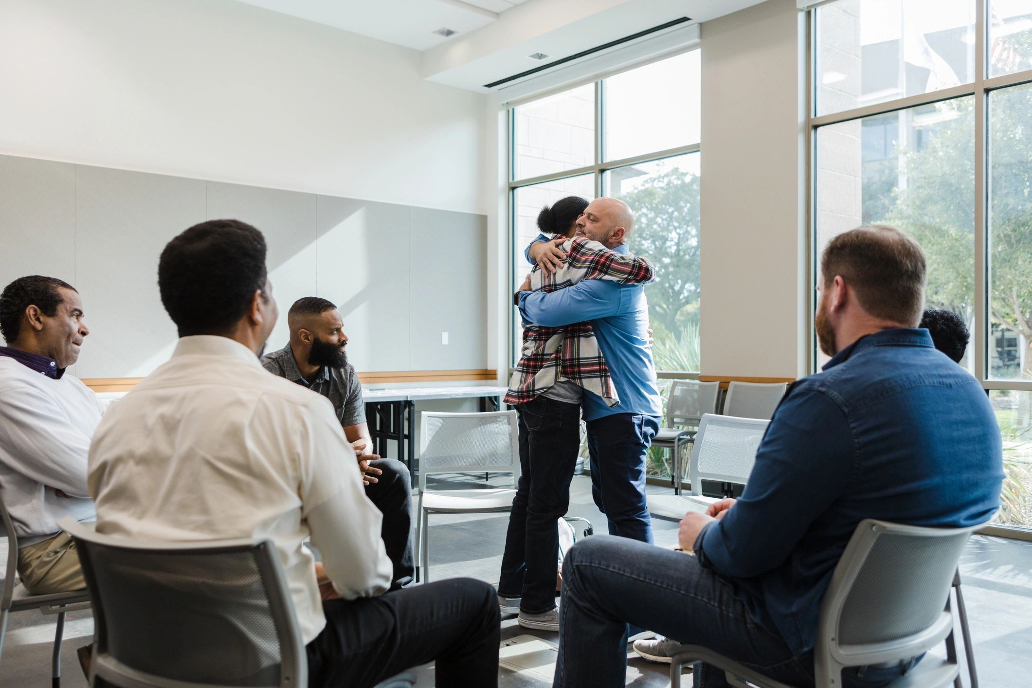 People supporting each other with a comforting hug in a recovery setting